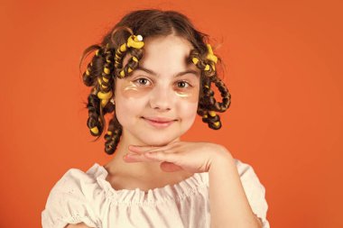 Mükemmel görünüyor. Kuaförde oynayan, saç bigudili mutlu kız. Çocuklar için saç stili yapmak için kolay ipuçları. Kuaför aletleri ve saç aksesuarları. Yüzü yamalı çocuk. Saç bigudileriyle poz ver