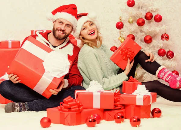 Pareja enamorada disfruta de la celebración navideña. Mujer y hombre barbudo usan sombrero de santa claus fondo del árbol de navidad. Nochebuena con cariño. El amor es el mejor regalo. Familia pareja casada en casa — Foto de Stock