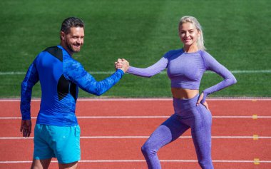 Koçla antrenman. Fitness partnerleri. Atletik erkek ve kadın bilek güreşinde yarışıyorlar. Stadyum koşu pistinde erkek ve kadın koç. Sağlıklı bir yaşam tarzı. Mutlu spor çifti takımı kazandı.