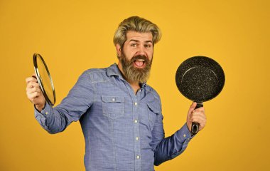 Mutfak gereçleri. Mutfak aletleri. İsimsiz dökme demir pişirme kabı. Tencerenin cam kapağı. Yapışkan olmayan kaplamalı politetrafluoretilen teflon. Adam yeni marka tavayı tutuyor. Sağlıklı yemek pişirmek.