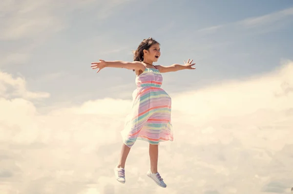 Sentir-se livre. Miúdo salta de vestido. salão de cabeleireiro feminino. beleza e moda de verão. criança alegre no fundo do céu. miúdo da moda ao ar livre. infância feliz. menina pequena tem cabelo longo e exuberante — Fotografia de Stock