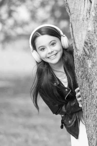 Baby tech. Happy child wear headphones outdoors. Small girl listen to music in headphones. Protecting hearing. Noise cancelling headphones. New technology. Headphones your child will appreciate