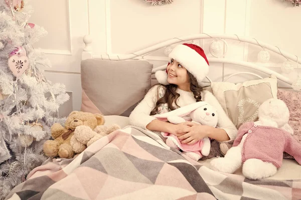 마법의 아침이야. 집이 참 좋네요. 크리스마스 장식을 하고 침대의 불빛 속에서 쉬고 있는 꼬마 소녀. 아늑 한 방. 어린 아이는 침실에서 휴식을 취한다. 아이는 긴장을 풀고 침대에 누워 있다. 크리스마스 이브 컨셉 — 스톡 사진