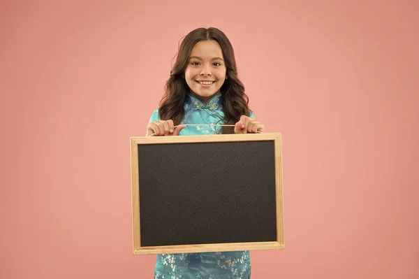 学校の広報。幸せな子供は黒板のピンクの背景を保持します。きちんとした広報板で小さな子供の笑顔。広告と宣伝。公共機関だ。学校のマーケティングキャンペーン、コピースペースに戻る — ストック写真
