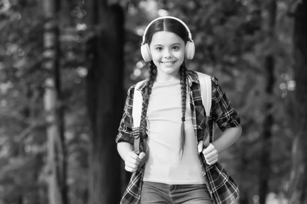 Podłącz, posłuchaj tego. Szczęśliwe dziecko słuchać muzyki naturalnej na zewnątrz. Mała dziewczynka nosić słuchawki w stylu casual. Nowa technologia. Wakacje. Odkrycie i przygoda. Uspokój się i słuchaj. — Zdjęcie stockowe