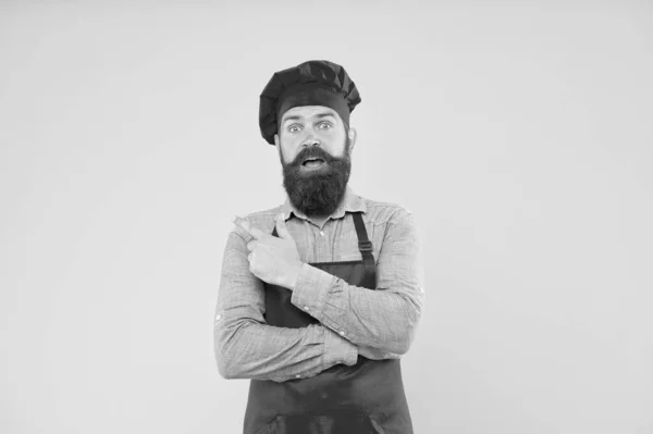 Yemek bizim uzmanlık alanımız. Kırmızı üniformalı erkek aşçı. Olgun hipster işaret ediyor. Tatmin olmuş sakallı şef. Önlüklü vahşi kasap. En iyi menü teklifi. Kendine güvenen mutlu şef beyaz üniforması — Stok fotoğraf