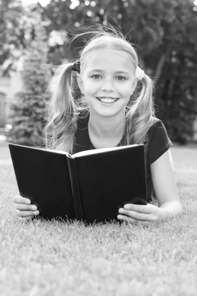 Літній читальний клуб. Щаслива дівчина читала книжку на зеленій траві. Літній список читання. Літня відпустка. Шкільні канікули. Відпочинок та дозвілля. Детальніше цього літа — стокове фото
