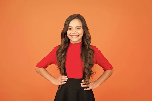 Ik hou van haar nieuwe schoolstijl. Gelukkige kindbruine achtergrond. Een kinderglimlach in schooluniform. Klein kind draagt lang golvend haar. Schoonheidssalon. Mode en stijl. Kinderopvang en kindertijd — Stockfoto