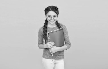 Edebiyat ve yaratıcılık. Mutlu çocuk okulda edebiyat okuyor. Küçük kız kitapları sarı arka planda tutuyor. Edebiyat dersi. İngiliz edebiyatı ve dili. Okul kütüphanesi. Eğitim ve eğitim