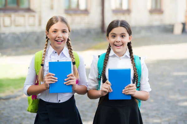 Happy children in school uniforms hold study books outdoors, knowledge
