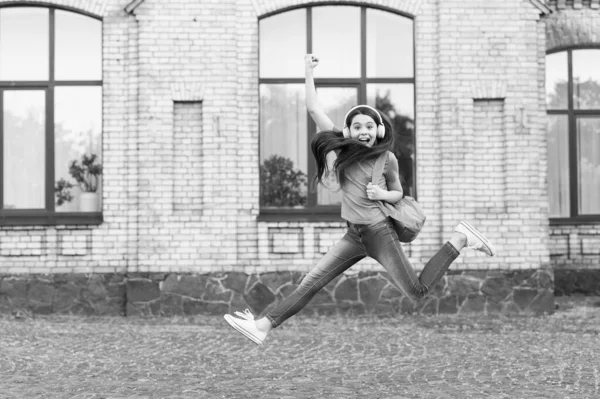 De feestdagen komen eraan. Gelukkig kind vieren feestdagen buiten. Actief meisje springt naar muziek. Schoolvakanties. Zomervakantie of vakantie — Stockfoto