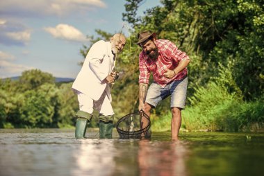 En iyi hafta sonuydu. İki erkek arkadaş birlikte balık tutuyor. Yakalama ve balık tutma konsepti. Mutlu balıkçı arkadaşlığı. Emekli baba ve olgun sakallı oğul. İş adamının uçan balık hobisi. emeklilik balıkçılığı