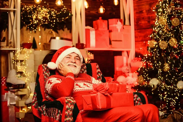 Papai Noel relaxando em cadeira de braço. Papai Noel, um idoso barbudo. Conceito de tradições. Avô idoso em casa. Lenda sobre o Pai Natal. Feliz Natal! Feliz Natal! Entregar presentes. Presentes para a família — Fotografia de Stock