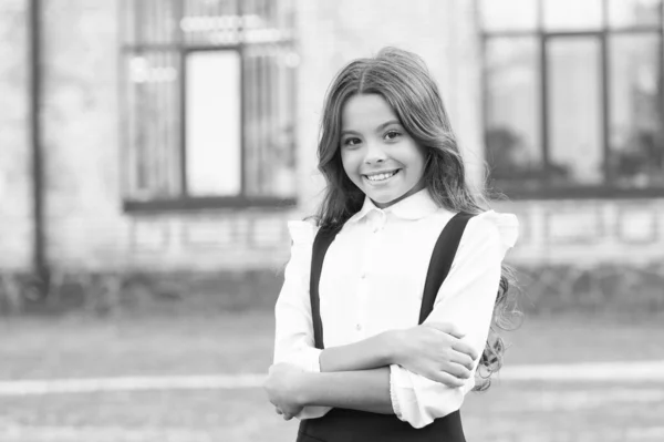 Aluna alegre com cabelo longo. aluno sorrindo criança usar uniforme. de volta à escola. feliz dia das crianças. menina com as mãos cruzadas ao ar livre. moda para crianças. primavera dia ensolarado — Fotografia de Stock