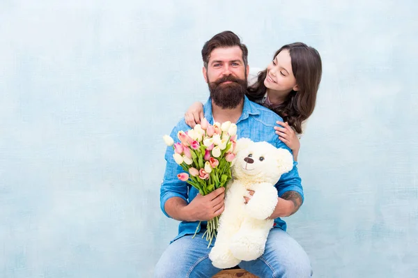 Отец и дочь обнимаются с весенним цветочным букетом тюльпанов и игрушкой плюшевого медведя, День отца — стоковое фото