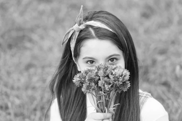 Flores de primavera traen nueva vida. Un niño pequeño sostiene flores al aire libre. Belleza mirada de niño pequeño. Floristería. Hora de verano. Celebración festiva. Flores y regalos para ella. Floreciendo a la vida — Foto de Stock