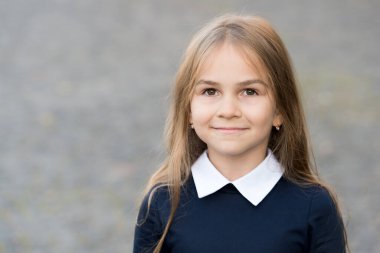 Uzun saçlı sevimli küçük bir çocuk okul üniforması giyiyor açık havada, kreşte, fotokopi odasında.