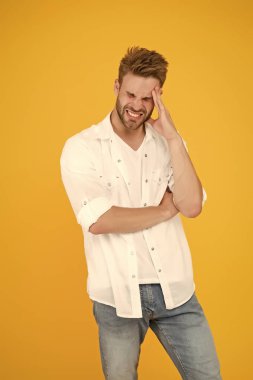 Başım ağrıyor. Kot gömlekli genç ve yakışıklı bir adam. Kot pantolon ve beyaz tişört giyen adam. Beyaz gömlekli adam. Pantolon sarısı arka planda yorgun ve stresli bir adam. moda ve insanlar konsepti