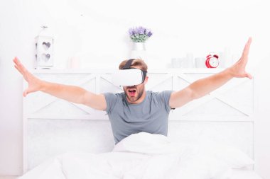 Geleceğe adım atmak. Yatakta sanal gerçeklik kulaklığı takan yakışıklı bir adam. Gelecek vizyonu. Eğlencenin ve iletişimin geleceği. Gelecek konsepti