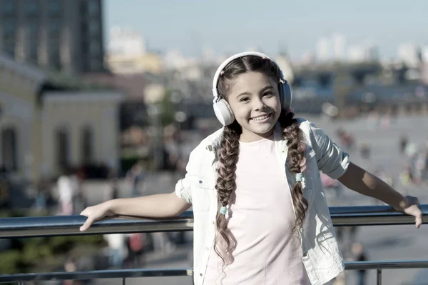 Ο κόσμος πέρα από τα ακουστικά μου είναι πολύ χαοτικός. Ένα κοριτσάκι που φοράει ακουστικά σε αστικές εξωτερικές περιοχές. Χαριτωμένο παιδί ακούγοντας μουσική στο αυτί στερεοφωνικά ακουστικά. Μοντέρνο μικρό παιδί φορώντας σύγχρονα ακουστικά — Φωτογραφία Αρχείου