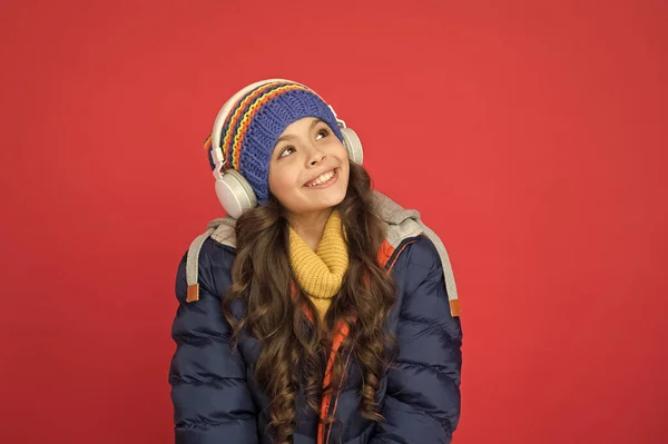 Música para o inverno. Criança feliz ouvir música fundo vermelho. A menina usa auscultadores a tocar música. Nova tecnologia. Vida moderna. Diversão e entretenimento. Gosto da minha música em voz alta — Fotografia de Stock