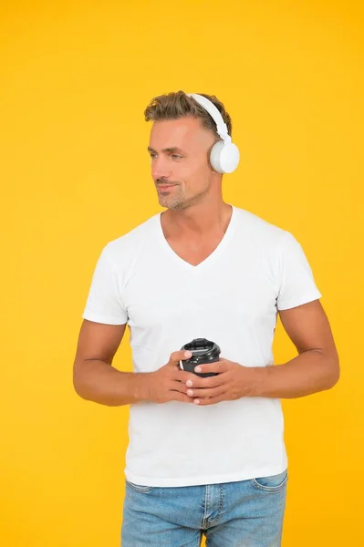 Bonito homem de meia-idade ouvir música bebendo café da manhã fundo amarelo, café da manhã — Fotografia de Stock