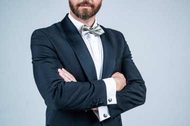 Tıraşsız sakallı, kendine güvenen damat şık bir smokin ve papyon giyer.