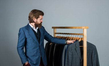 Özel dikim takım elbiseli bir adam pahalı bir smokin giyiyor. Butikte erkek kıyafetleri. Takım elbiseli adam. Atölyesindeki terzi. Klasik kostümlü yakışıklı sakallı moda adamı.