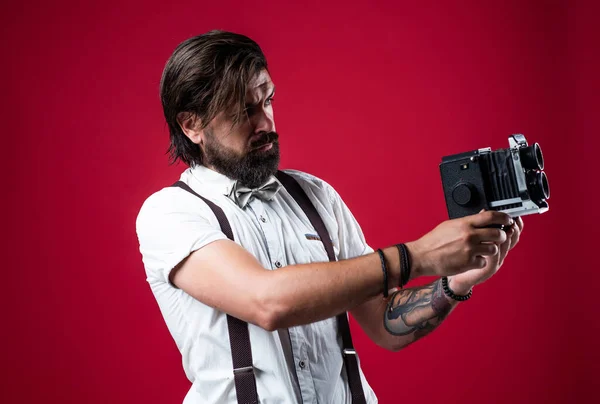 Fotografering. Retroman i hängslen och fluga. säker elegant fotograf hålla klassisk kamera. journalist med vintage fotokamera. Formellt partireporter. gammaldags skäggig hipster — Stockfoto