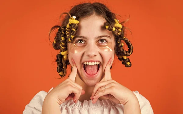 Amuse-toi bien. outils de coiffure et accessoires pour cheveux. gamin avec des patchs sur le visage. pose avec des bigoudis. fille heureuse dans les bigoudis jouant salon de coiffure. Conseils faciles à faire coiffure pour les enfants — Photo