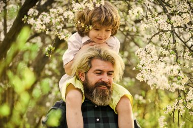 Baba ve oğul çiçek açan ağaçta. Bahar zamanı birlikte. Küçük çocuk babasıyla mutlu. Aile eğleniyor. Parkta çiçek açan ağaç. çocukluk ve ebeveynlik mutluluğu. Sevgi ve destek