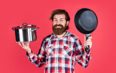 Şef yemek yapıyor. Tavalı kareli gömlekli olgun bir adam. Şık erkek yemek pişirecek. Bıyıklı sakallı adam mutfak aletleri kullanıyor. Sağlıklı yemek. Yapışmayan yüzey. Gururun iştahı.