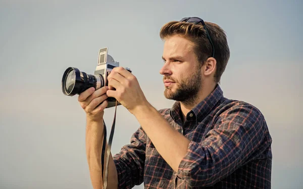 Reportero tomando fotos. Equipo vintage. Blogger disparando vlog. Tiempo de vacaciones. Guapo blogger chico viajero cámara retro. Tipo al aire libre cielo azul de fondo. Concepto de fotoperiodista. Blogger de viajes — Foto de Stock