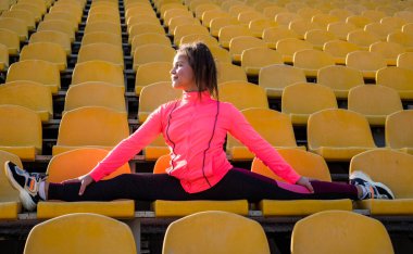 İyi esneme hareketleri. esnekliği böl. Beden eğitimi dersinde çocuk eğitimi. Kız antrenmandan önce geriniyor. Jimnastikçi yarışmaya hazırlan. Sporcu stadyum tribününde ısınıyor.