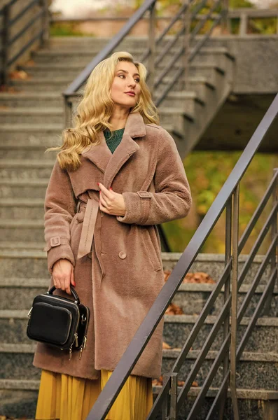 Feeling cold. sexy blong woman. autumn season. european winter. girl warm coat stairs background. faux fur coat fashion. stylish business lady leather bag. glamour girl look luxuriously — Stock Photo, Image