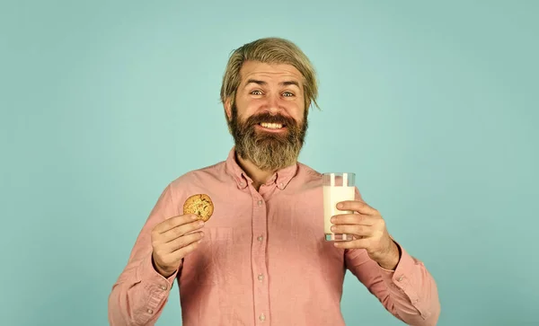 Het concept van gezond eten. Biologische landbouwproducten voor ontbijt of lunch. melk en koekjes. gelukkige boer eet koekjesdessert. bebaarde man drinkt nuttige melk met gebak — Stockfoto