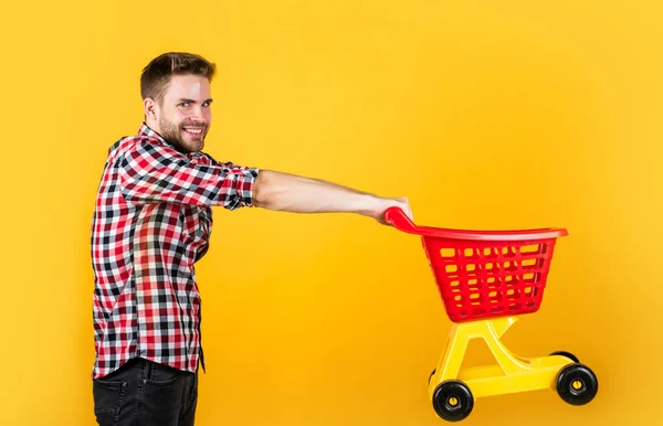 Macho elegante transportar carrinho de compras. Homem barbudo na loja. comprar e comprar. Preparem-se para férias. De casa. Um verdadeiro viciado em compras. jovem cara em camisa quadriculada ir às compras — Fotografia de Stock