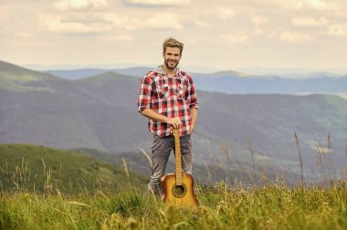 Dağların sessizliği ve gitar tellerinin sesi. Hippi müzisyen. İlham verici bir ortam. Dağda gitarlı bir müzisyen. İlham verici bir müzisyen. Açık havada yaz müzik festivali. Müzik çalınıyor