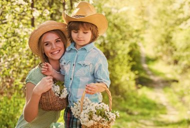 Benim tatlı bebeğim. Çiftlik konsepti. Büyüyen çiçekler. Mutlu aile günleri. Şapkalı bir anne ve yakışıklı bir oğul. Aile çiftliği. Birlikte vakit geçirin. Güzel bir aile doğa geçmişi var. Çiçek açan bahçede çiftçiler