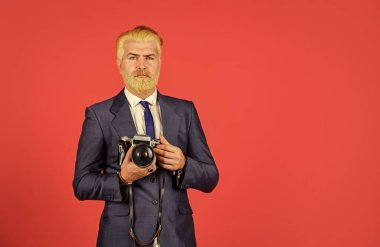 Elle ayarlar. Sarışın sakallı ve bıyıklı bir fotoğrafçı. İçerik yaratan. Sakallı hippi fotoğrafçı. Fotoğrafçı retro kamerayı beklesin. Vintage değerler uzmanıyım. Şık ve eski moda.