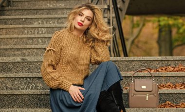 Sonbahar moda trendi. Kız eteğinin üstüne daha büyük bir katman örülmüş. Giyilebilir trendler. Sonbahar formülü. Sonbahar için Süveter ve Etek Kombo stili. Muhteşem saç stili olan kadın merdivenlerde dışarıda oturuyor.