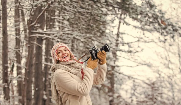 Femme tenant un appareil photo. prendre des photos dans la forêt d'hiver. Photographe photographiant un jour d'hiver enneigé. femme heureuse vêtements chauds mode. vacances Voyage d'hiver. élégant voyageur hipster — Photo