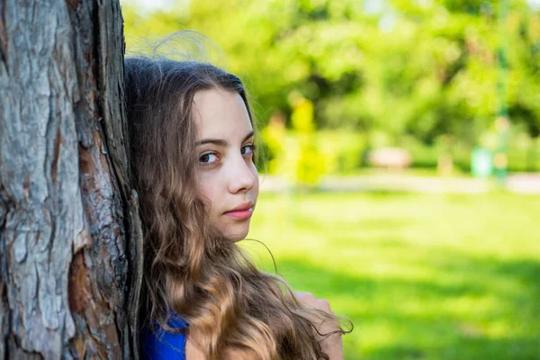 女の子長い巻き毛の木の幹にもたれ、自然と団結 — ストック写真