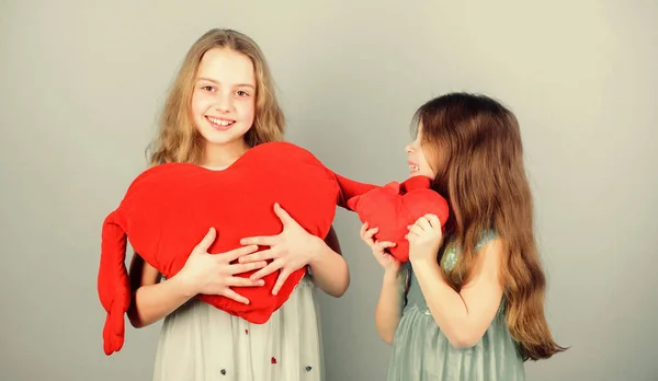 Sincere kids share tenderness and love. Girls hug red plush heart toy symbol love. Sisterhood concept. Valentines day. Friendly relations siblings. Family love. Happy feeling love. Loving sister — Stock Photo, Image