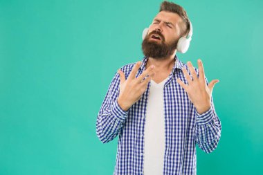 Sakallı ve bıyıklı beyaz adam dijital kulaklıkla müzik dinlemenin keyfini çıkarıyor.