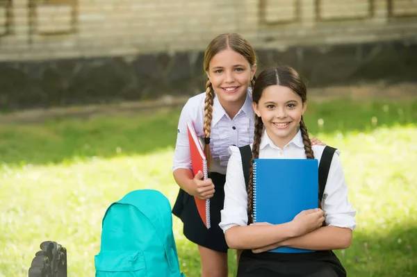 Des enfants heureux en uniforme tiennent des livres scolaires pour faire leurs devoirs à l'extérieur, l'éducation — Photo