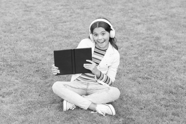 Var smart. Söt tjej läser bok. Glad förskoletjej med bok på skolgården. Tillbaka till skolan. hårt arbetande barn i hörlurar. begreppet utbildning och läsning. utveckling av fantasin — Stockfoto