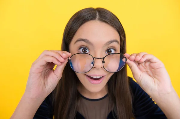 Erstaunt intelligentes Mädchen Kind mit langen Haaren und Brille auf gelbem Hintergrund, Überraschung — Stockfoto
