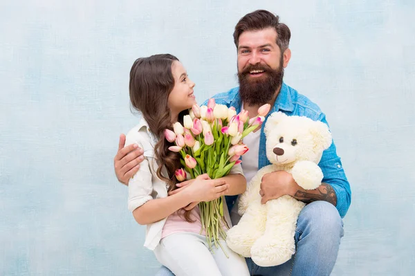 Dotter och far firar födelsedag. Flicka hälsning pappa med fäder dag. Glad familjeporträtt med nallebjörn. vårblombukett. Kvinnodagen. förbereda tulpaner för mödrar dag — Stockfoto