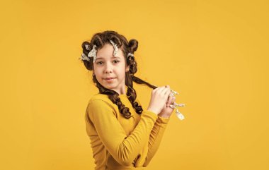 Folyo saç kıvırma numarası. Çocuk kuaför salonu. Sağlıklı, uzun saç stili. Çocuk için saç bakımı. Küçük kadın tımar ediyor. Güzellik ve moda. Küçük kızın folyo saç bigudileri var. Tüm folyo paketlerini kaldır